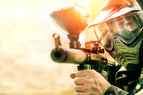 Paintball player Close-up of a paintball player wearing mask and aiming a weapon. About 25 years old, Caucasian male. paintballing stock pictures, royalty-free photos & images