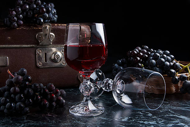 istock Glass of red wine on dark marble background. Blue grapes 635680164