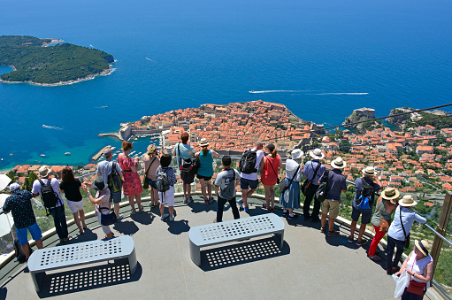 Dubrovnik, Croatia - June 20th 2016. Tourists view the historic city of Dubrovnik from the viewing platform by the cable car  on the hill above the city. The island of Lokrum can be seen in the distance.