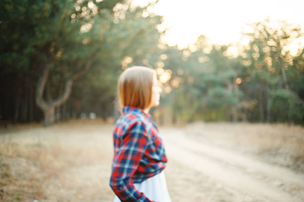 Unfocused bride walks through the woods. Wearing a white dress and a plaid shirtUnfocused bride walks through the woods. Wearing a white dress and a plaid shirt
