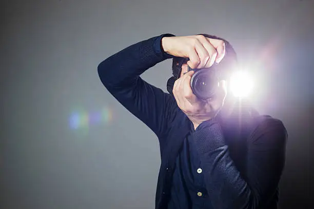 Young man takes a picture on a camera with built-in flash. Bright light for illumination of the frame.Young man takes a picture on a camera with built-in flash. Bright light for illumination of the frame.