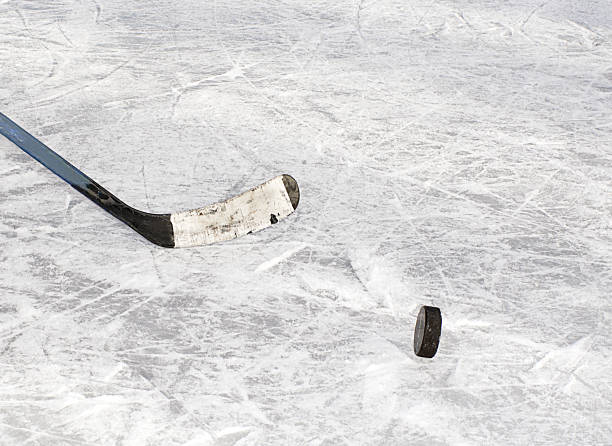 istock Hockey puck and stick on ice 635699950
