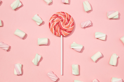 Sweet marshmallows minimalism set with red lollipop on pastel rose petal background