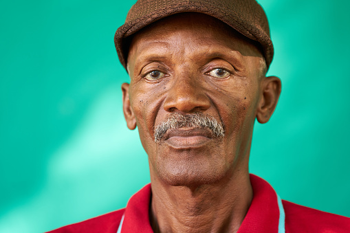 Real Cuban people and feelings, portrait of sad senior african american man looking at camera. Worried old latino grandfather with mustache and hat from Havana, Cuba