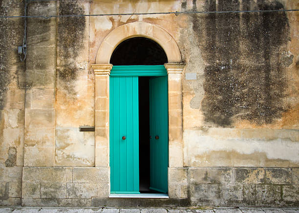 Italian House: Vibrant Arched Green Door in Mottled Wall Italian house: a vibrant arched green door (ajar) in a mottled yellow house. Shot in Sicily. ajar stock pictures, royalty-free photos & images