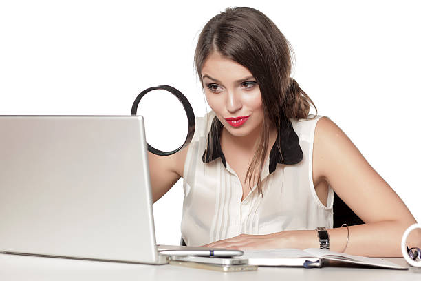 giovane donna guardando il suo portatile con una lente d'ingrandimento - private secretary foto e immagini stock