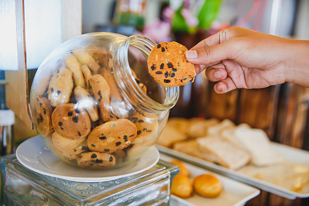 uomo adulto che prende gocce di cioccolato dal barattolo - biscotti cookie morning temptation foto e immagini stock