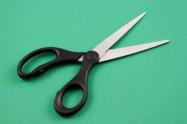 istock Black Handled Scissors On A Green Background 635723184