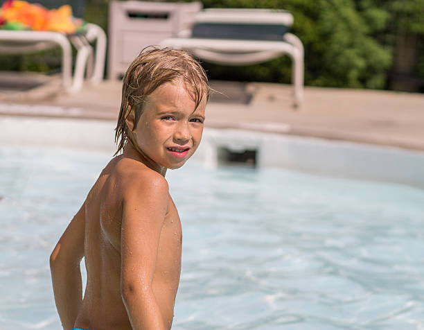 istock Portrait of a boy sitting by the pool 635724288