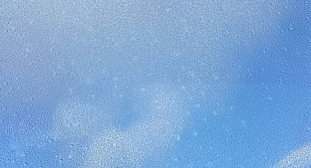 istock Water drops on glass with blurred blue sky background 635726100