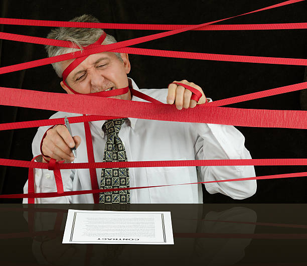 frustrated business man caught in red tape stopping progress - red tape imagens e fotografias de stock