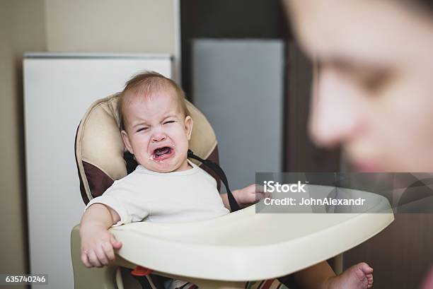 Mom Feeds The Baby Who Is Naughty Stock Photo - Download Image Now - Baby - Human Age, Child, Childhood