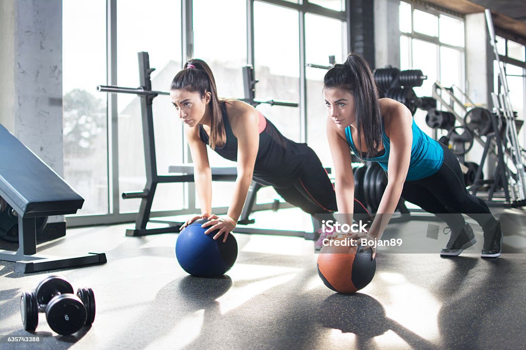 Young women doing stretching exercises on fitness ball in gym. Exercising Stock Photo