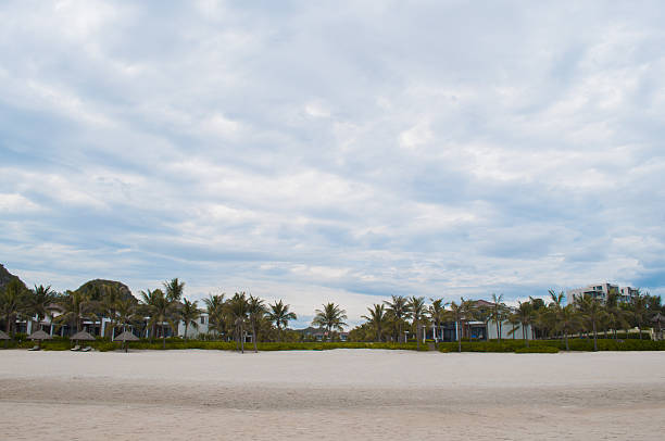 My Khe beach with white sand, straw parasols and palms in Danang, Vietnam