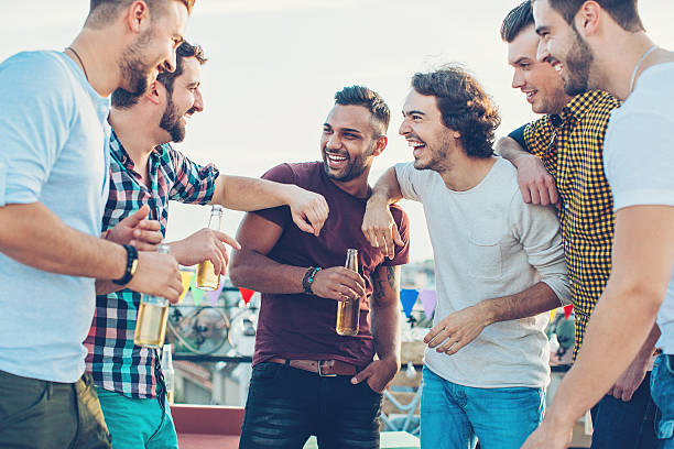 Boys only drinking beer and chatting Group of young men chatting and drinking on a rooftop party. stag stock pictures, royalty-free photos & images