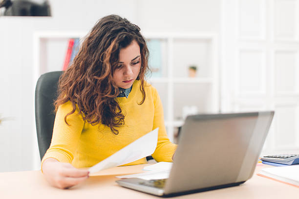istock Businesswoman holding document and using laptop in modern office 635757044
