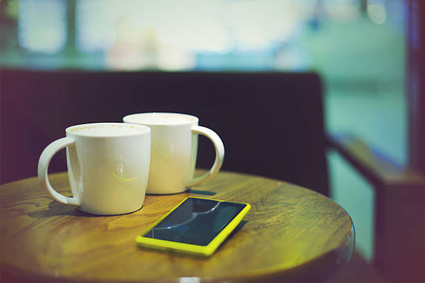 Coffee cups in coffee shop and mobile phone. Modern communication concept