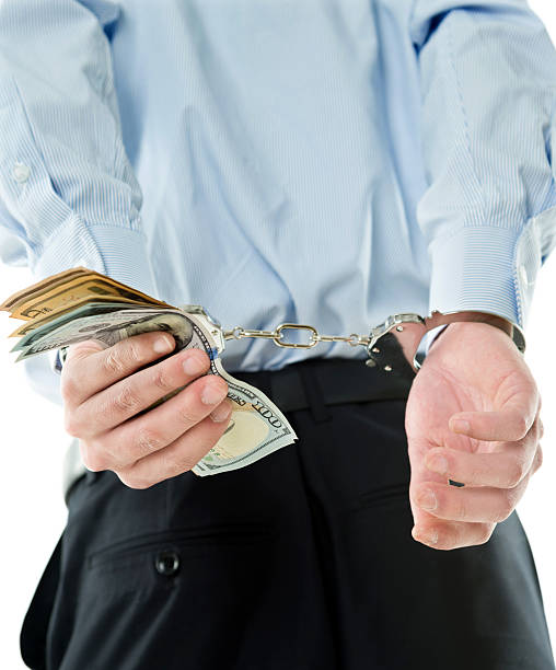 istock Businessman hands in handcuffs holding US dollars 635764926