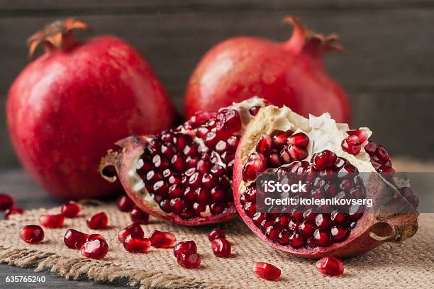 Two Pomegranate On The Old Wooden Board With Sackcloth Stock Photo - Download Image Now