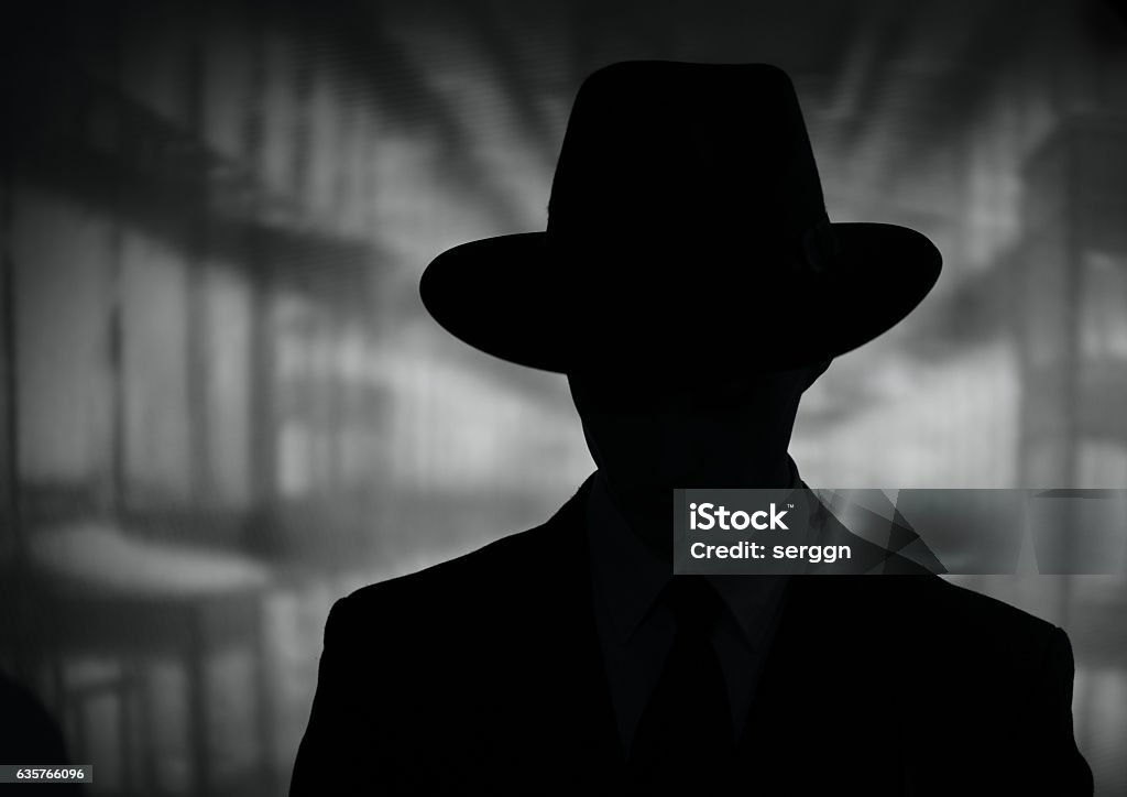 Silhouette of a mysterious man in a hat Silhouette of a mysterious man in a vintage style wide brimmed hat in a close up black and white head and shoulders portrait Villain Stock Photo