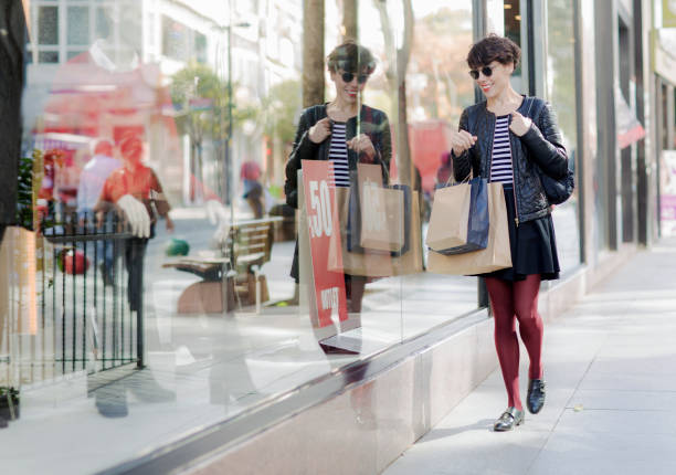 Woman looking at store window with her reflection on glass.