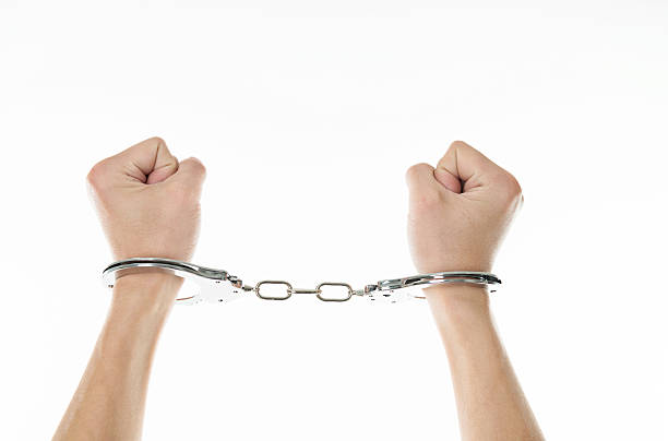 Close-up of man's hands in handcuffs isolated on white background.