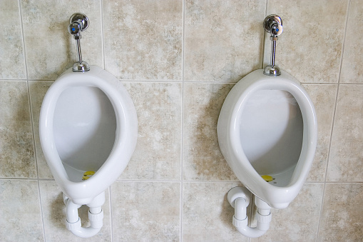 A pair of White porcelain urinals on a tile wall in a restroom