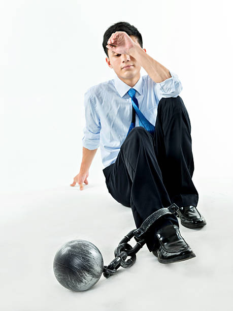 istock Businessman with ball and chain against white background 635767926