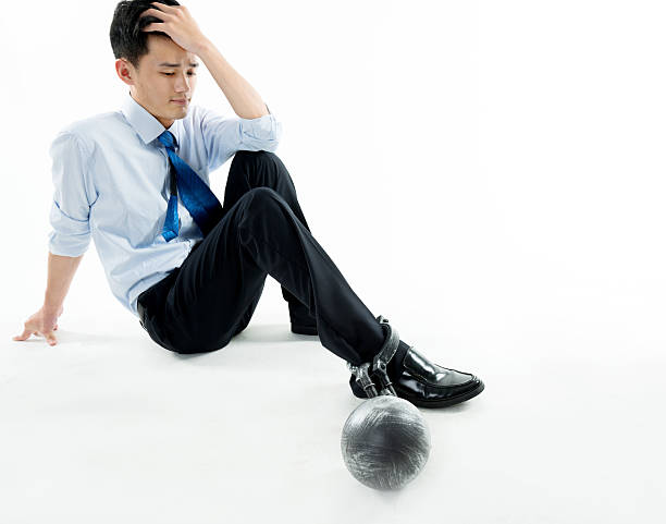 istock Businessman with ball and chain against white background 635768094
