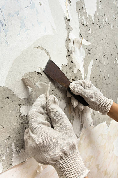 istock hands scraping off old wallpaper with spatula 635772582