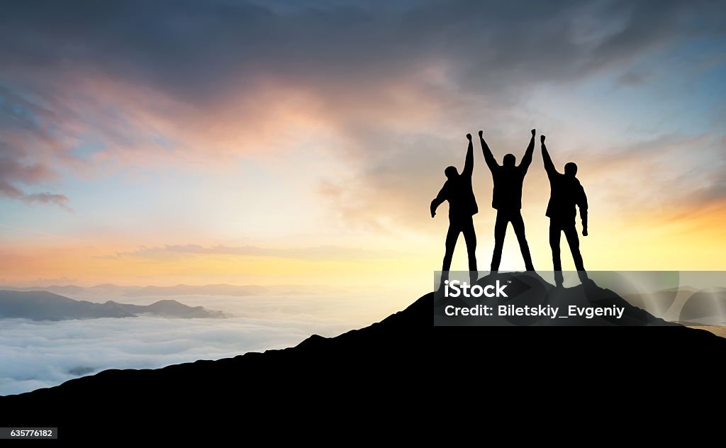 Silhouette of the team Silhouette of the team on the peak of mountain. Sport and active life. Mountain Stock Photo
