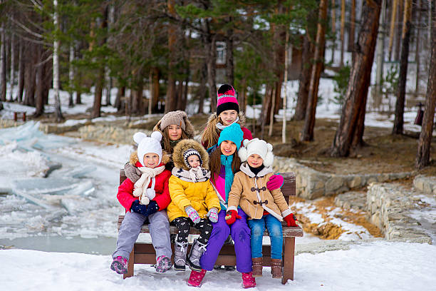 группа молодых девушек, сидящих на скамейке - winter river стоковые фото и изображения
