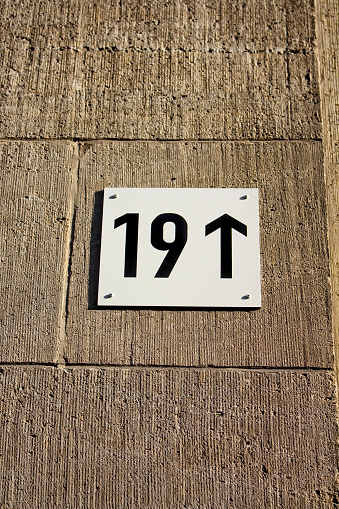 Modern building number with arrow showing up on stone wall in Berlin