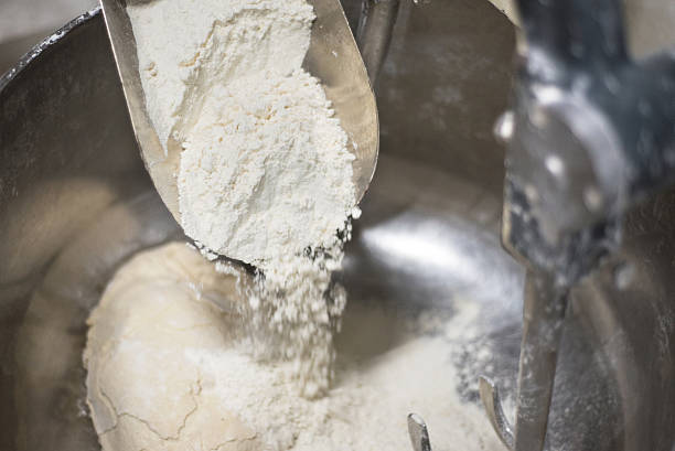 Loading flour into an industrial dough mixer. Loading flour into an industrial dough mixer. Close up view. electric mixer photos stock pictures, royalty-free photos & images