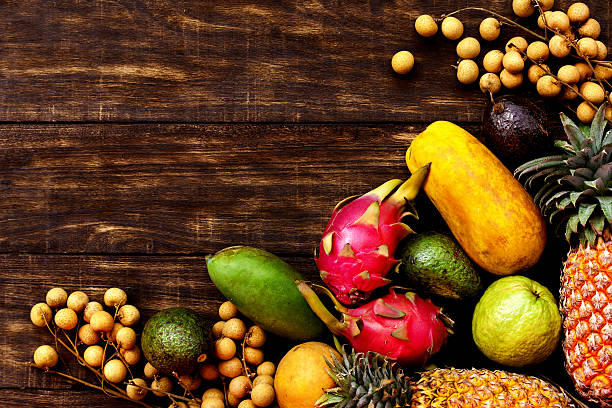 istock Tropical fruit on dark wooden background, top view 635779848