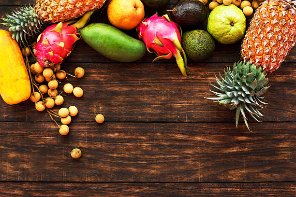 istock Tropical fruit on dark wooden background, top view 635779994