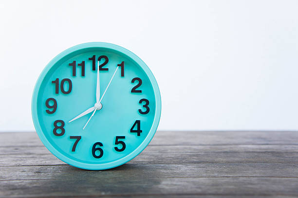 istock Green clock on a wooden table on a white background. 635781934