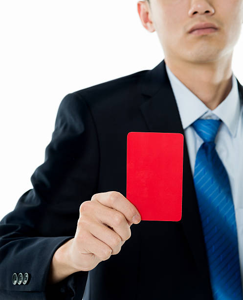 istock Young businessman holding red card against white background 635784662