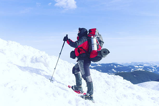 Winter hiking in the mountains on snowshoes with a backpack and tent.