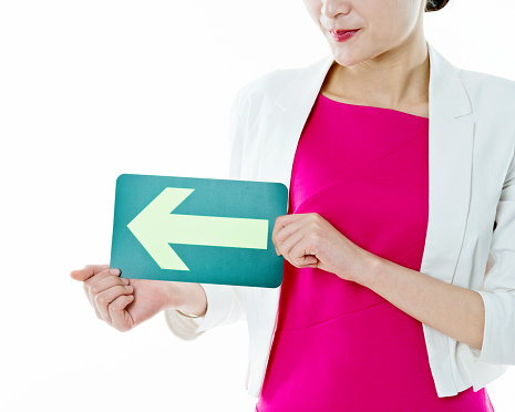 Businesswoman holding a green arrow forward against white background.