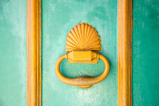 Old ancient door knocker on wooden door with vivid colors.