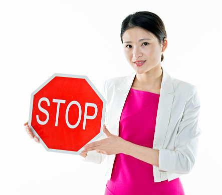 Young woman holding STOP sign against white background.