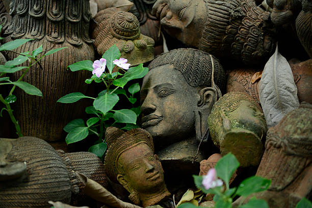 Three Buddha statues in a row. In the image the heads of the buddhas are shown from front side view and only the middle and right face are fully visable. The buddhas have their eyes closed and have a peaceful and zen like expression, looking to the right.