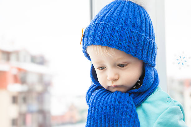 istock Sick child in warm clothes with sad look during winter 635799502
