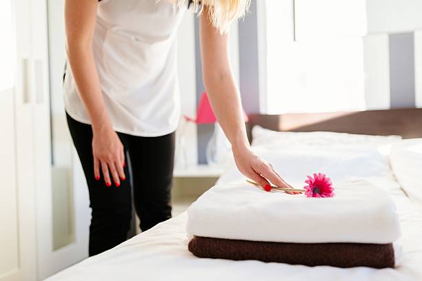 istock Young hotel maid placing flower on fresh towels 635800232