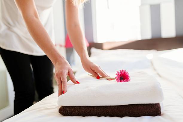 istock Young hotel maid placing flower on fresh towels 635800272