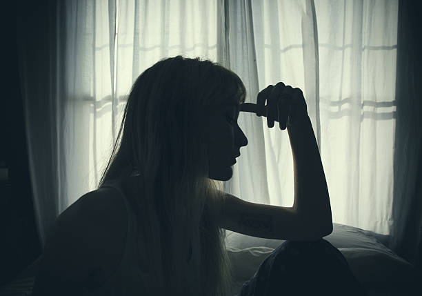 силуэт женщины, сидящей в постели у окна - silhouette women shadow window стоковые фото и изображения