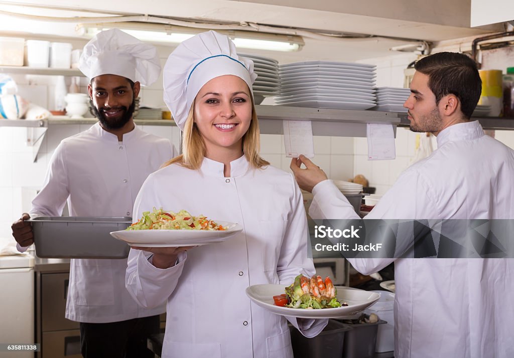 Crew of professional cooks working at restaurant Crew of happy american professional cooks working at restaurant kitchen Cafeteria Stock Photo
