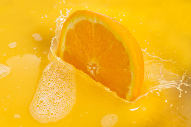 istock Orange Slices Splashing into Orange Juice on White Background 635811606