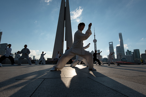 Shanghai, China - September 9, 2015: Silhouettes of Tai Chi practitioners in the early morning, skyline in background